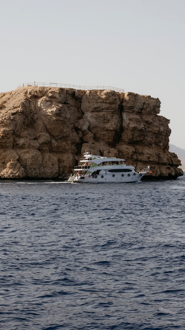 a boat traveling on the sea near the cliff in egypt